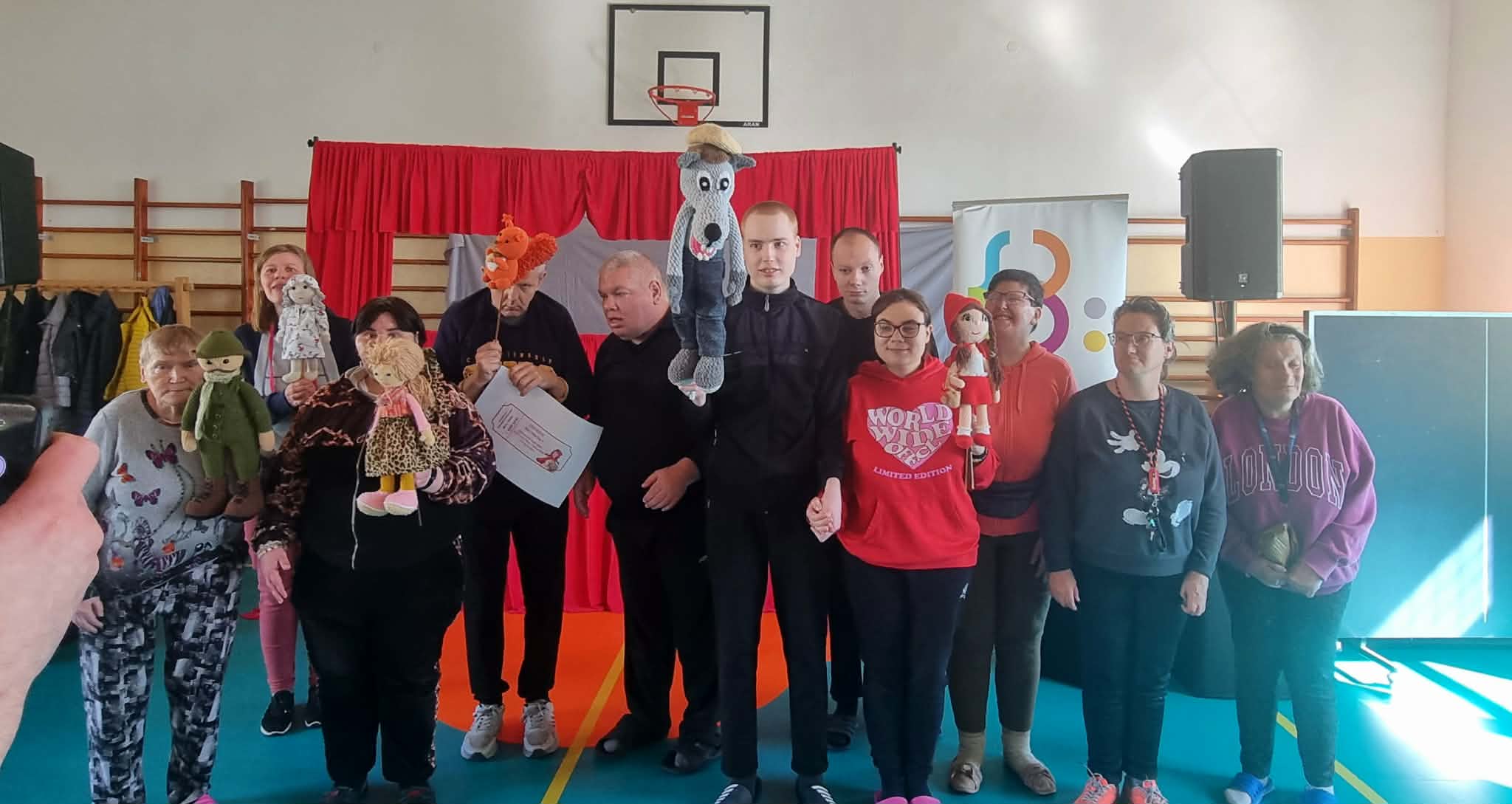 Widzowie pozują razem do wspólnego zdjęcia. Część z nich z entuzjazmem prezentuje maskotki, które zostały użyte podczas przedstawienia